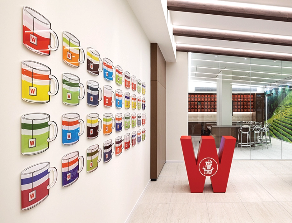 Spatial branding featuring 3D painted acrylic wall art, red logo sculpture, and custom printed wallpaper for Wissotzky.