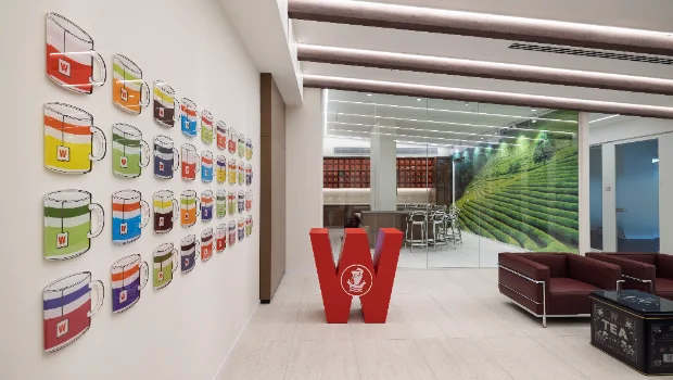 Spatial branding featuring 3D painted acrylic wall art, red logo sculpture, and custom printed wallpaper for Wissotzky.